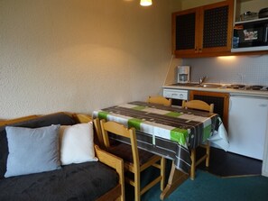 Eine kompakte Küchenzeile mit einem kleinen Esstisch und Stühlen, einem Sofa und einer Mikrowelle.