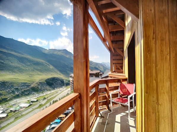 Enjoy breathtaking views of the surrounding mountains from this balcony with a comfortable chair.