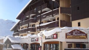 A multi-story building with balconies, a ski resort sign, and a restaurant sign. - 2-room apartment, 4 pers, ski-in/ski-out, wifi, pets allowed (Les Menuires)
