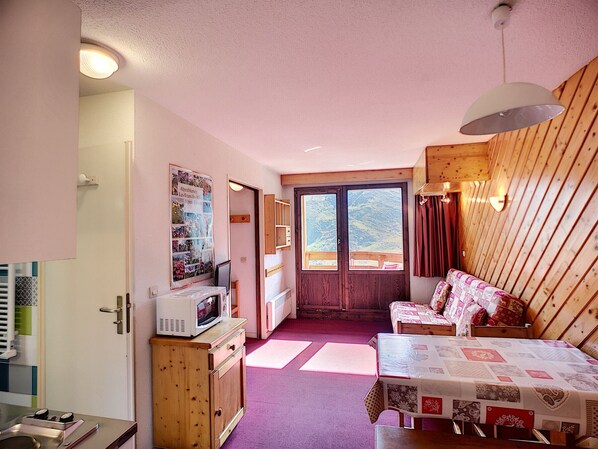 Ein kleines Zimmer mit Küchenzeile, Essbereich und Bett.