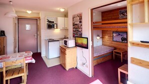 A compact room with a kitchenette, a bed, a small table, and a TV. - 2-room apartment, 4 pers, ski-in/ski-out, wifi, pets allowed (Les Menuires)