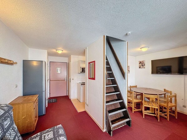 A compact living space with a kitchenette, a dining area, and a staircase. - Economic Apartment, 4 Rooms, Ski-In/Ski-Out, 6 Pers, Wifi, Parking (Les Menuires)