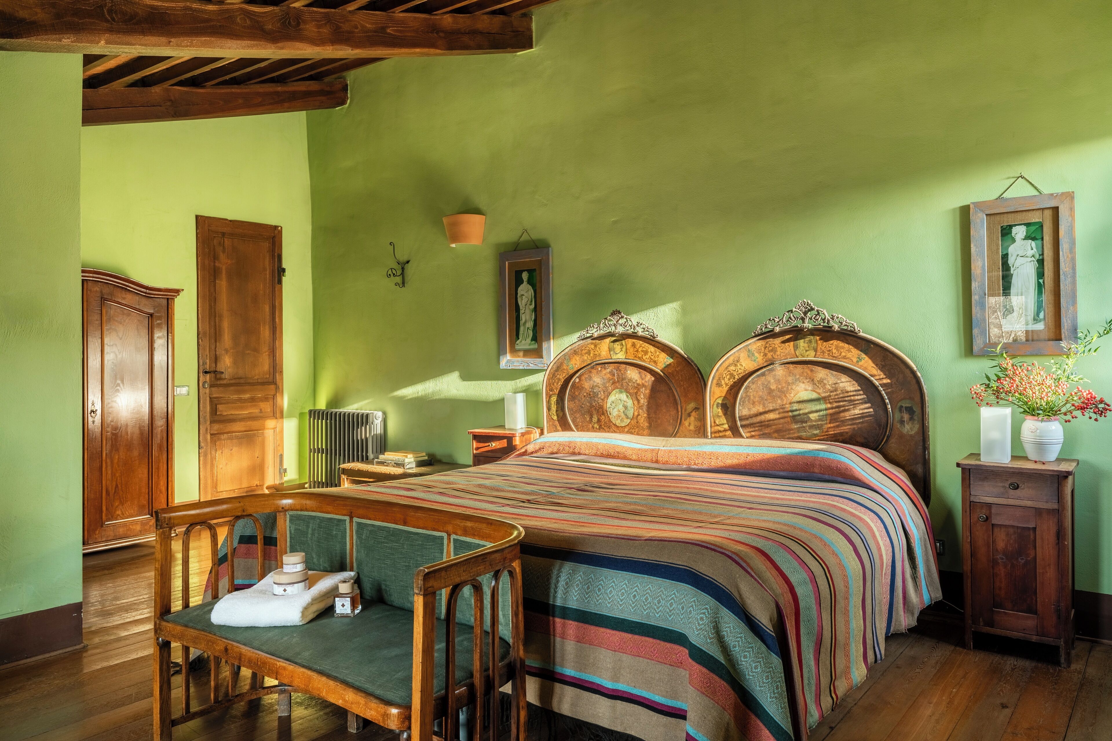 A room with a large bed, wooden furniture, and a green wall.