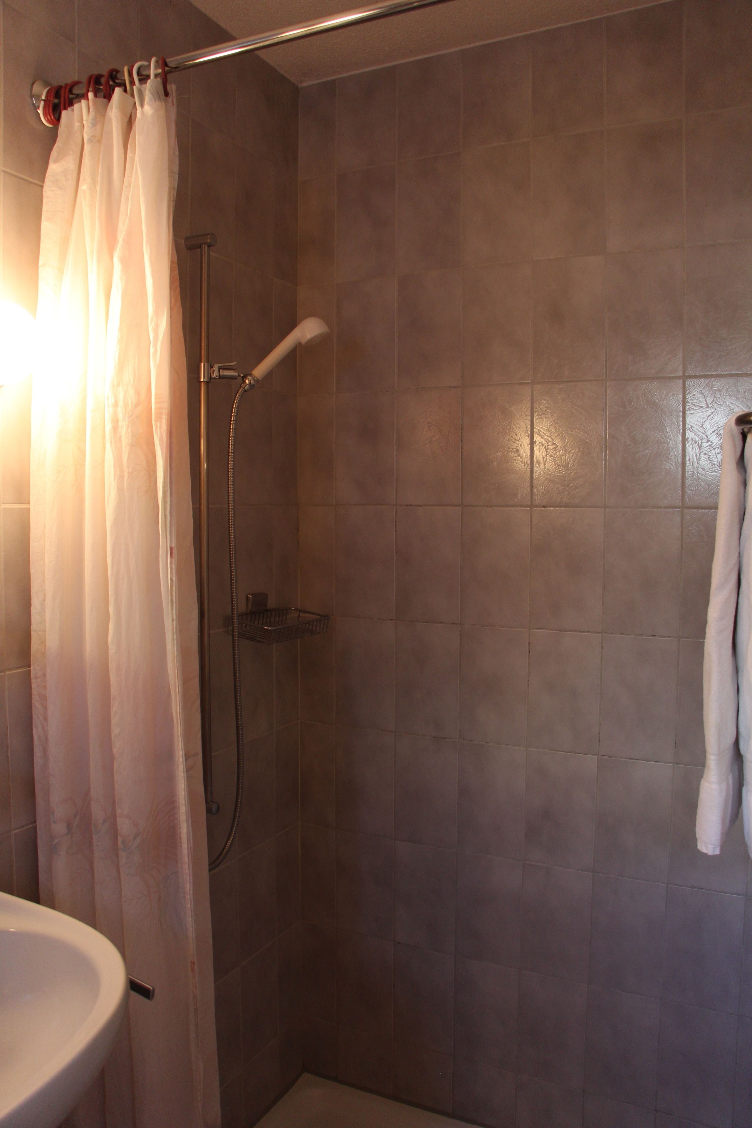 Un baño con ducha, lavamanos y barra para toallas.