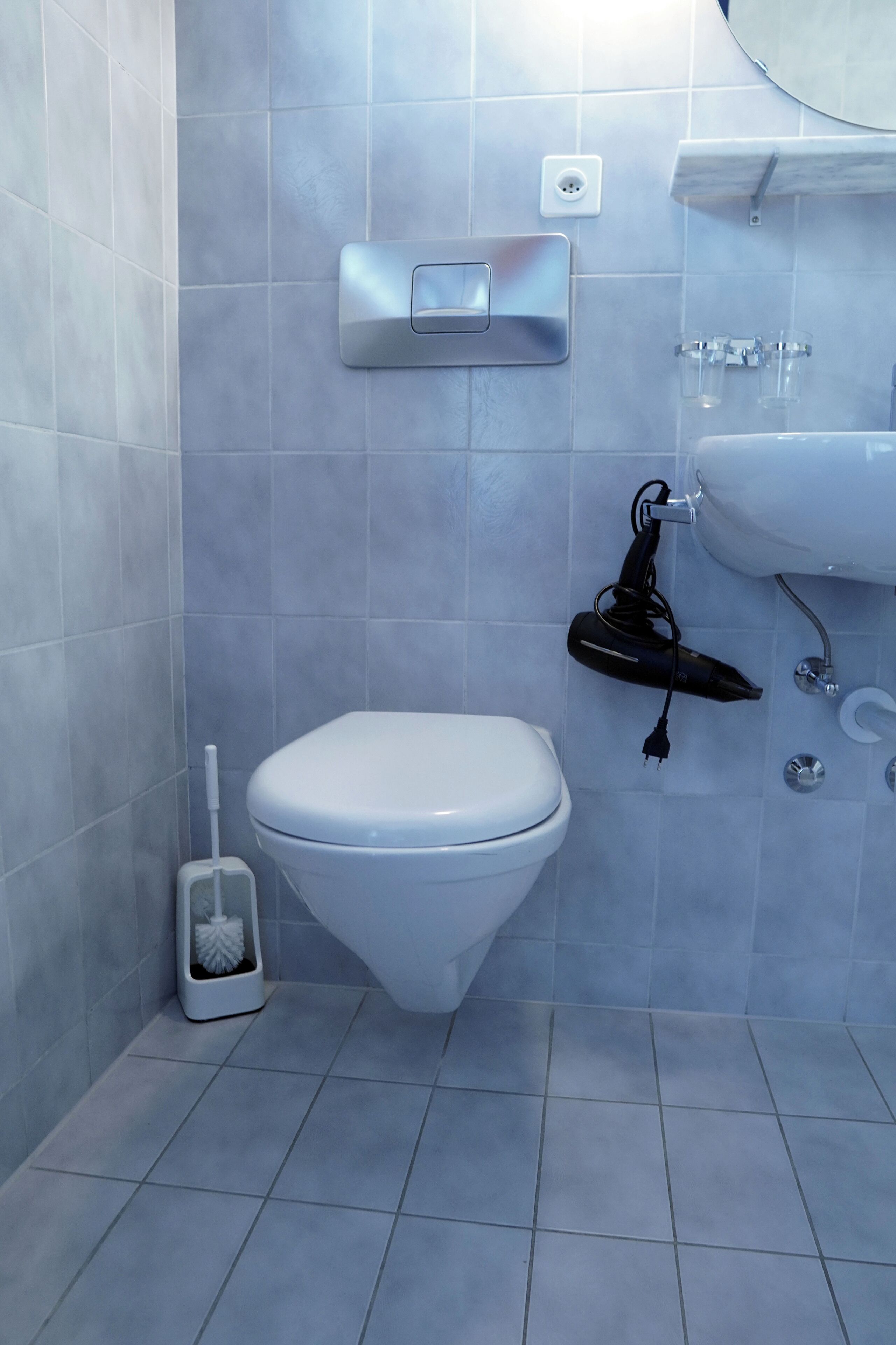 Een badkamer met toilet, handdroger, wastafel en spiegel.