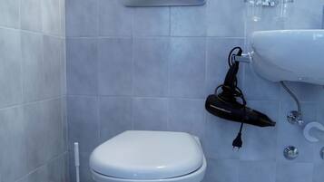 Een badkamer met toilet, handdroger, wastafel en spiegel.