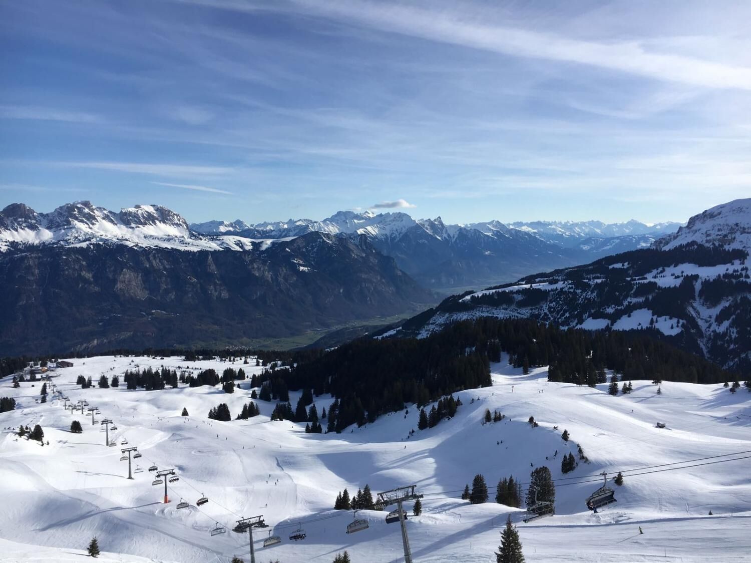 A snow-covered mountain landscape with ski lifts and a clear sky.