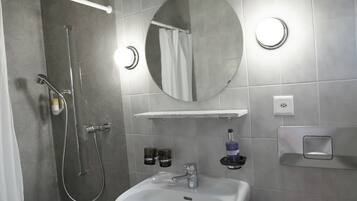 Une salle de bain moderne avec une douche, un lavabo et un miroir.