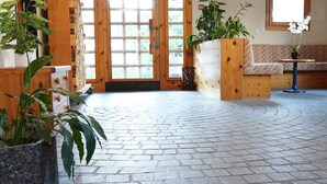 A reception area with a wooden door, a bench, and potted plants. - Hotel Schiffahrt (Quarten)