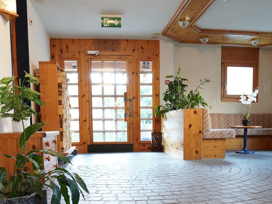 A reception area with a wooden door, a bench, and potted plants.