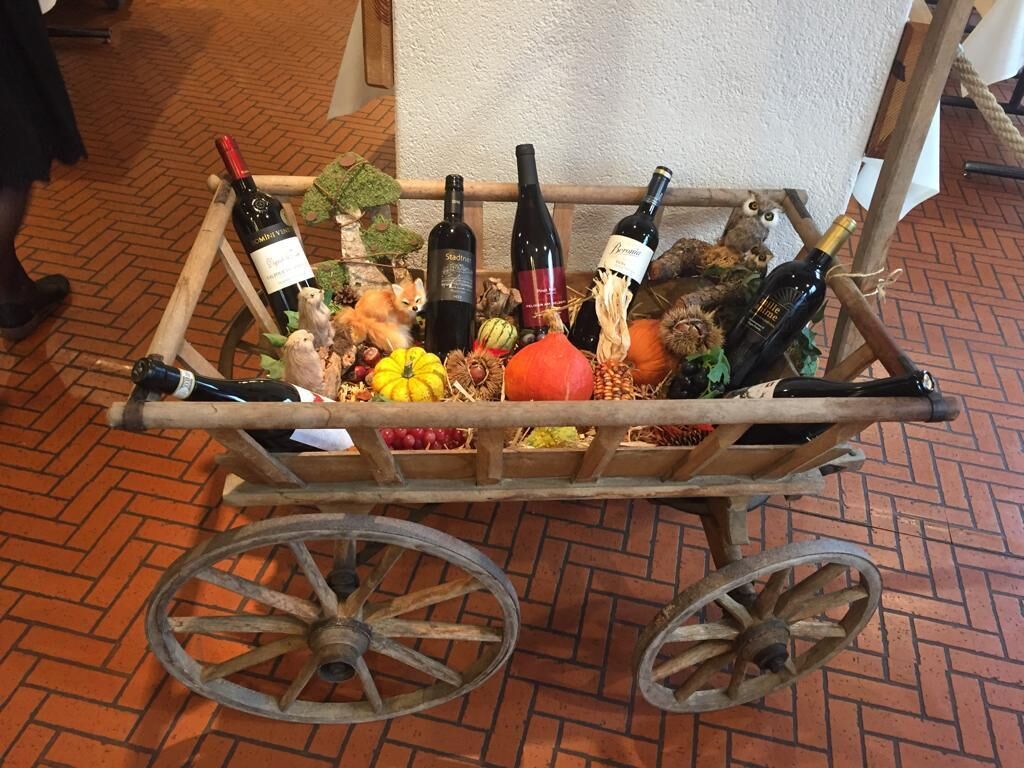 A cart with wine bottles and various fruits and vegetables.