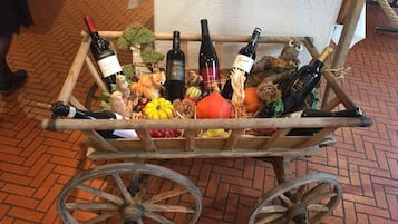 A cart with wine bottles and various fruits and vegetables.