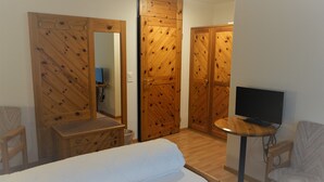 A bedroom with a bed, a TV, a desk, and wooden wardrobes. - Hotel Schiffahrt (Quarten)