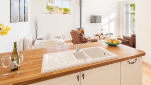 Une cuisine moderne avec un évier blanc, un plan de travail en bois et un coin repas avec une table mise pour deux personnes.