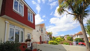 Een woonstraat met huizen, een palmboom en een heldere lucht.