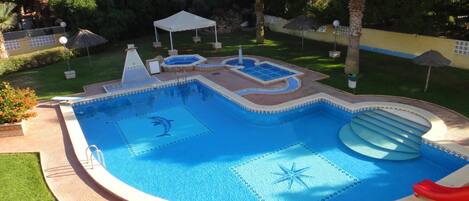 A swimming pool with a dolphin design, a slide, and a star pattern on the water.