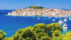 A coastal town with buildings on a hillside, boats in the water, and clear skies. - Holiday apartment with a view of the lake (Primošten)