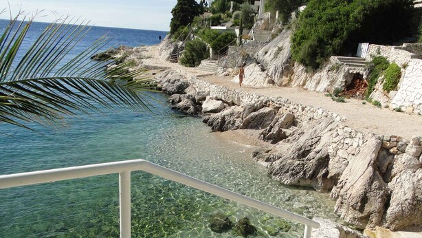 A coastal view with clear water, rocky terrain, and a staircase leading to a building. - Holiday apartment with a view of the lake (Primošten)