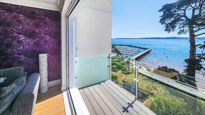 A balcony with a view of a marina and boats, a wooden floor, and a purple floral wall. - 2 bedroom accommodation in Torquay (Torquay)