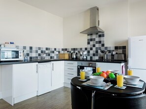 Eine moderne Küche mit Mikrowelle, Toaster und Spüle. Ein Esstisch steht bereit, mit Obst und Saft.