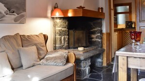 Ein gemütliches Wohnzimmer mit Kamin aus Stein, einer Couch und einem Tisch mit Gläsern.