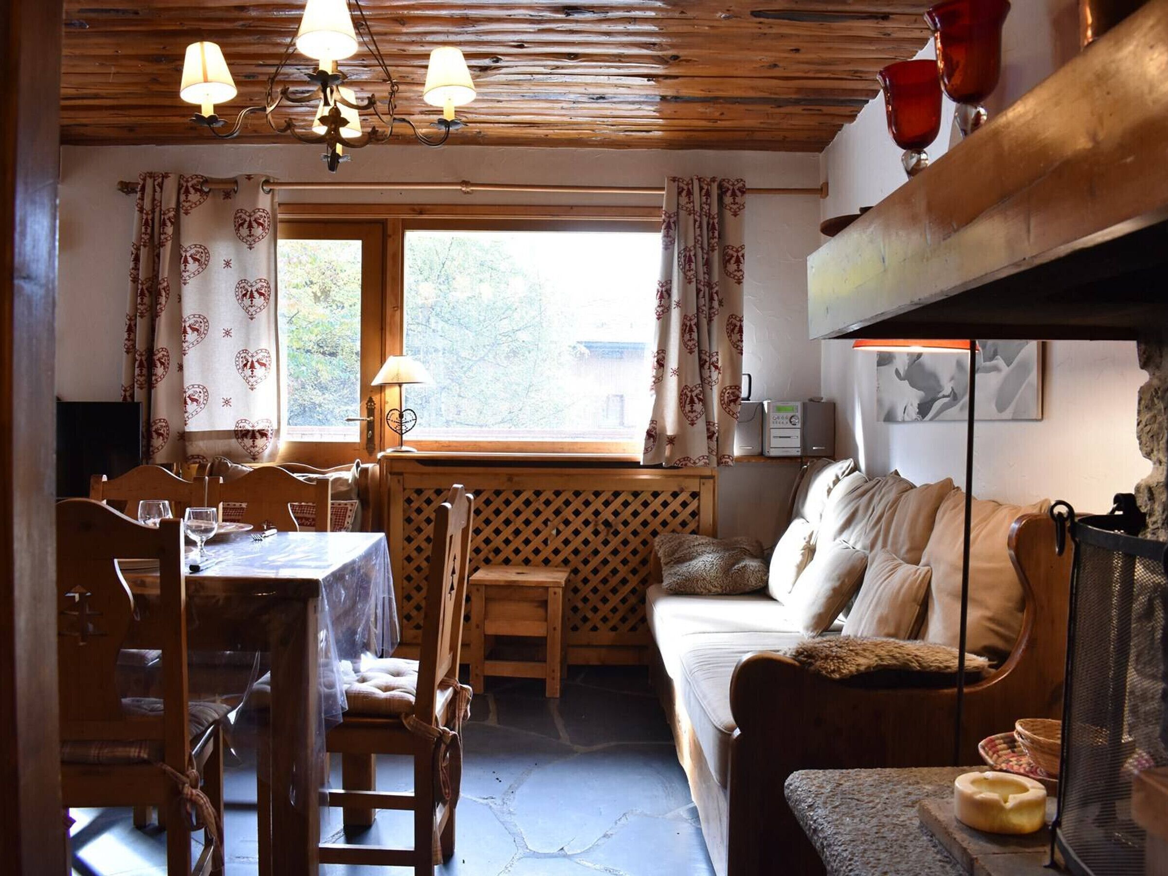 A cozy room with a wooden dining table, chairs, a sofa, and a fireplace.