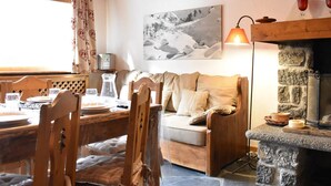 Ein gemütliches Zimmer mit einem Holzespeisetisch für zwei Personen, einer Couch und einem Steinkamin.
