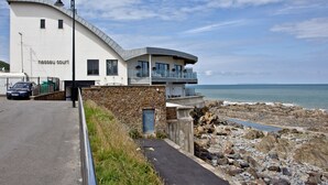 A coastal building with a curved facade, a balcony with glass railings, and a view of the sea. - The Penthouse Bay View (Westward Ho!)