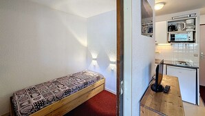 Espai vital reduït amb una banca, cuina americana i una petita zona de menjador.