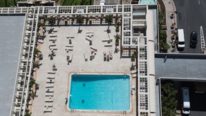 An aerial view of a hotel with a swimming pool surrounded by sun loungers and a covered area with tables and chairs. - BEST RATE!  ADA Studio Ala Moana Condominium (AH01) (Honolulu)