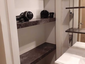 Minimalist design with a dark countertop, black speaker, and decorative item, paired with a white cabinet for storage.