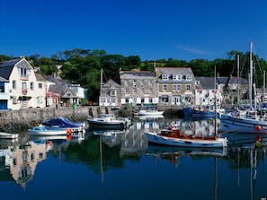 A harbor with boats docked, buildings with shops, and a clear blue sky.