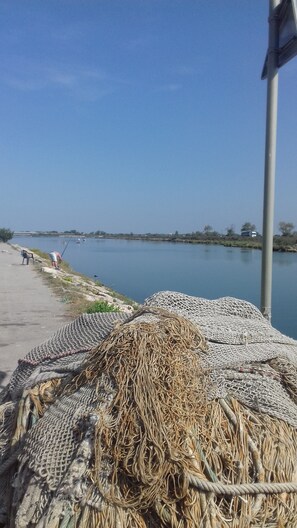 Une rivière paisible où l’on voit une personne pêcher, une pile de filets de pêche et une chaise sur la rive.