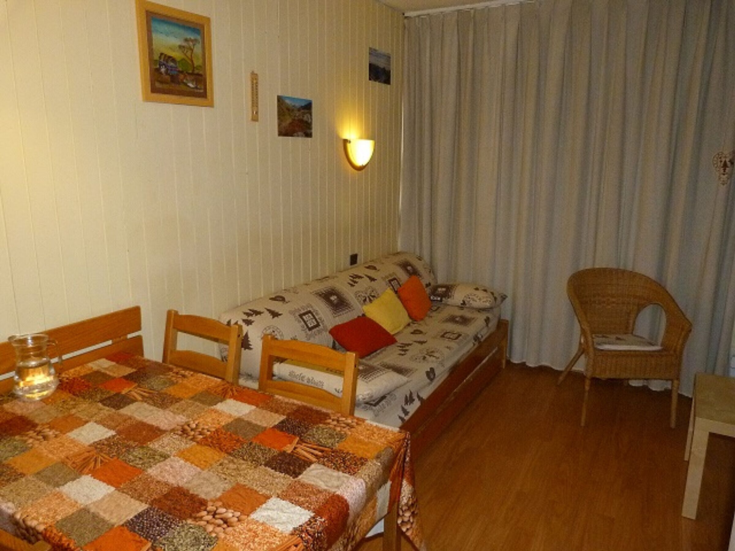 Ett mysigt rum med ett matbord i trä, en mönstrad soffa och en fåtölj i rotting.