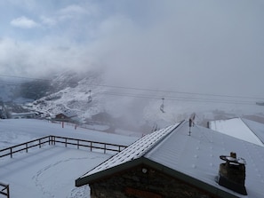 A snow-covered mountain with a ski lift and a stone building with a metal roof. - Cozy 2-room apt for 5, ski-in/ski-out (Les Menuires)
