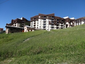 Un edificio residencial de varios pisos con un diseño arquitectónico moderno, que cuenta con balcones y un techo plano.