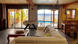 A spacious living area with a sofa, a foosball table, and a view of the ocean. - FRONT de MER, Standing Villa, 20 m from the Ocean, swimming pool, Saint-Pierre - (Saint-Pierre)
