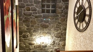 A staircase with a stone wall, a clock, and a small window. - FRONT de MER, Standing Villa, 20 m from the Ocean, swimming pool, Saint-Pierre - (Saint-Pierre)