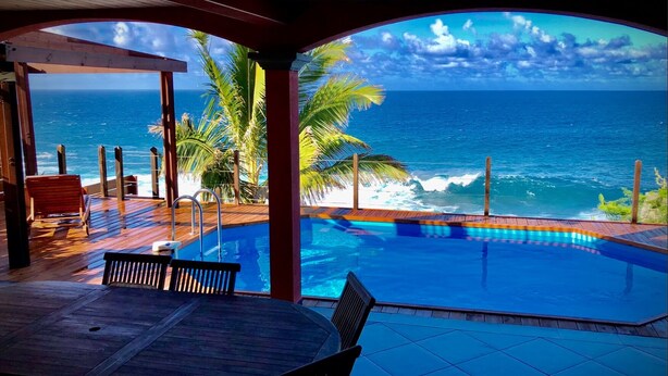 A pool with a view of the ocean and palm trees. - FRONT de MER, Standing Villa, 20 m from the Ocean, swimming pool, Saint-Pierre - (Saint-Pierre)