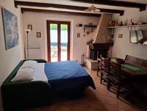 Un dormitorio con cama, escritorio, chimenea y vistas a través de una puerta.