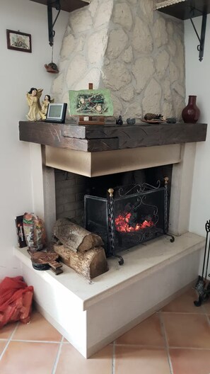 Una chimenea con repisa de piedra, un reloj y una pequeña figura de ángel.