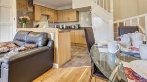 Une cuisine moderne avec des meubles en bois, un îlot central et un coin repas comprenant une table et des chaises en verre.