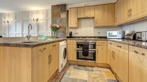 Une cuisine moderne avec des meubles en bois, un four encastré, un four à micro-ondes et un lave-linge.