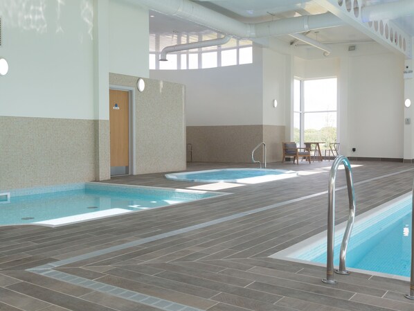 Une piscine intérieure avec des murs carrelés et une porte en bois.