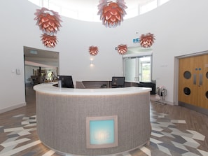 A reception desk with a woven texture, a digital screen, and a patterned floor.