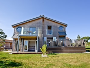 Ein zweistöckiges Haus mit Terrasse, großen Fenstern und einem kleinen Garten.