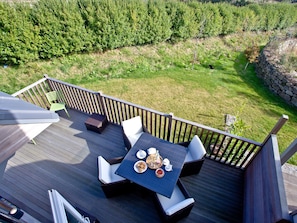 Eine Terrasse mit Gartenmöbeln, einem gedeckten Tisch und Blick auf die umliegende Natur.