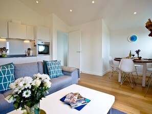 A modern living room with a sofa, coffee table, and dining area with chairs.