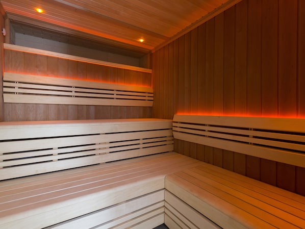 A sauna with wooden benches and a sloped ceiling.