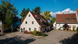 A traditional building with a sloped roof, a small porch, and a sign indicating it is a local inn. - Übernachten in der Tenne (Nuremberg)